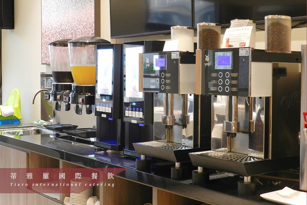 A row of coffee machines with digital displays and a beverage dispenser.