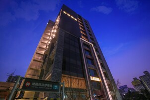 A high-rise hotel with illuminated signage, a visible parking sign, and a clear view of the sky.