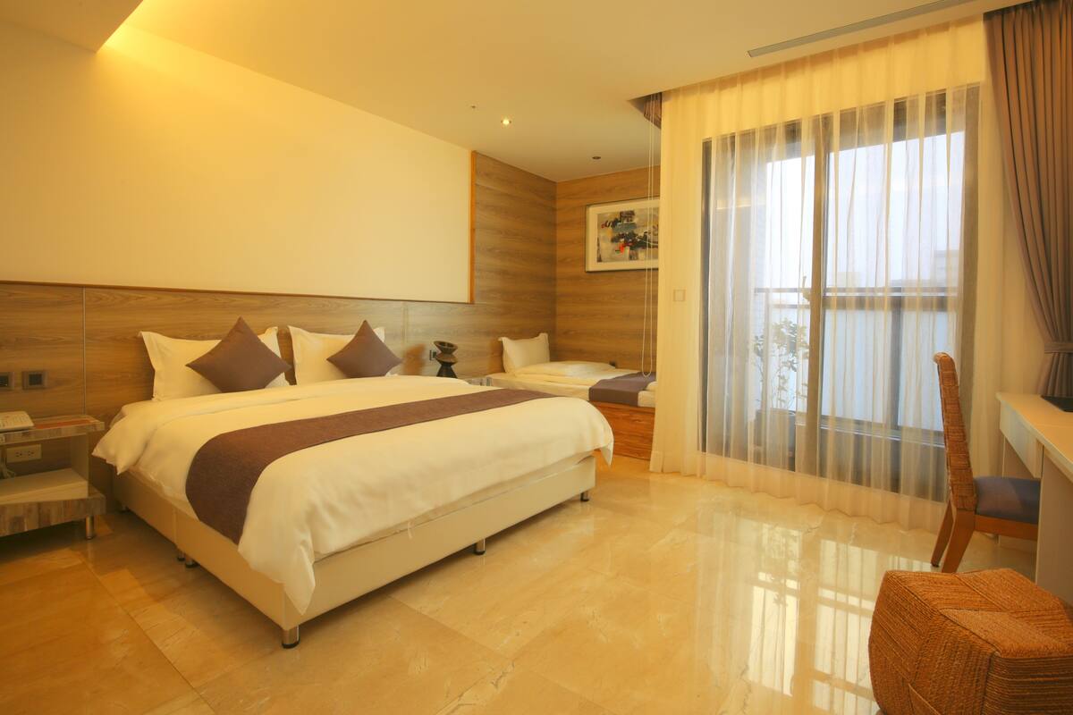A modern hotel room with a large bed, a desk, and a chair.