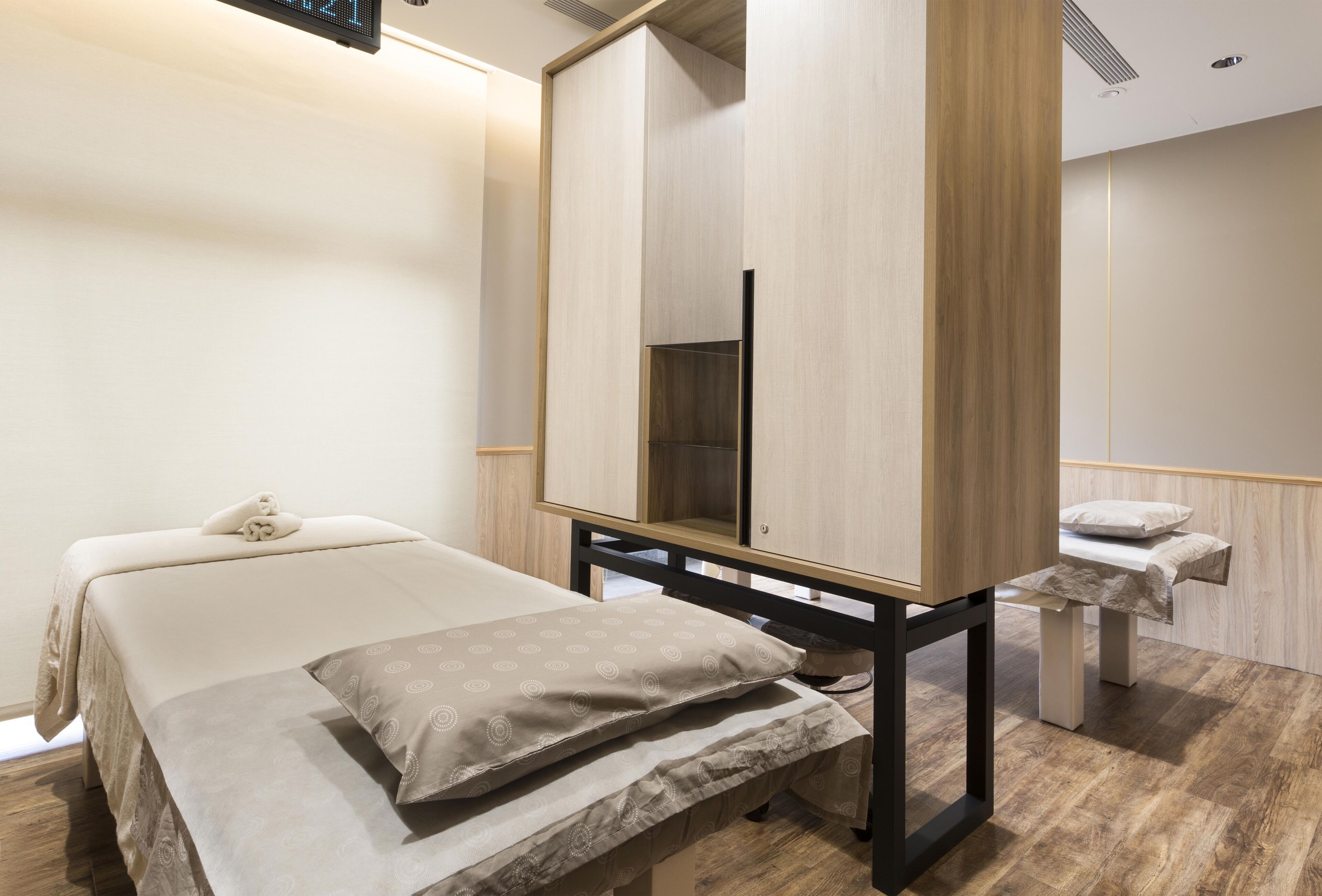 A modern hotel room with a bed, bedside table, and a mirror cabinet.