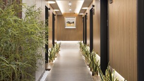 A modern hotel corridor with a long, dark tiled floor, wooden panel walls, and potted plants along the sides. - Dar Lon Hotel (Hsinchu)