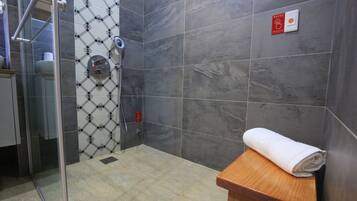 A bathroom with a shower, a toilet, and a towel on a wooden counter.