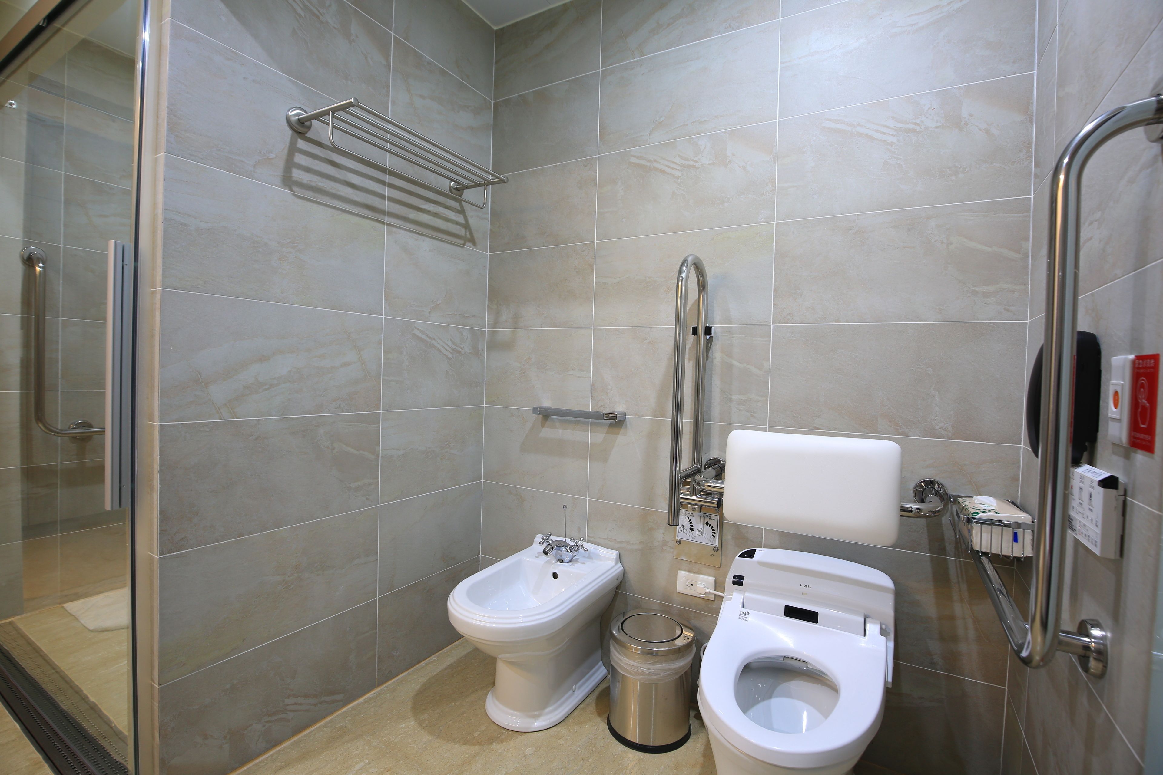 A modern bathroom with a bidet, a toilet, and a glass-enclosed shower area.