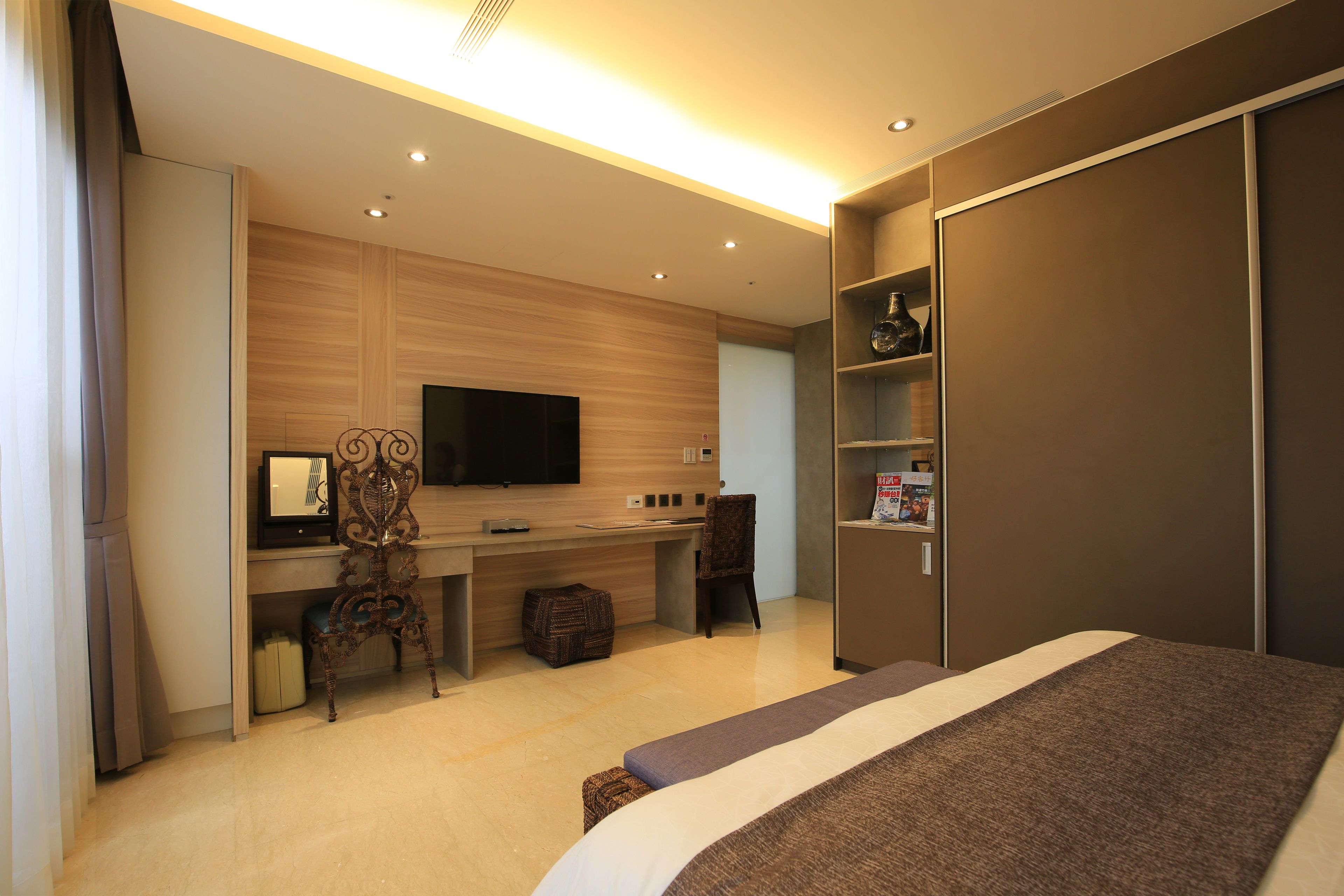 Habitación de hotel moderna con una cama grande, un escritorio, un televisor de pantalla plana, una silla y un armario.