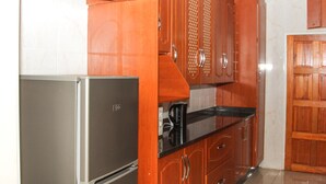 Una cocina con armarios de madera, un refrigerador de acero inoxidable y una encimera negra.