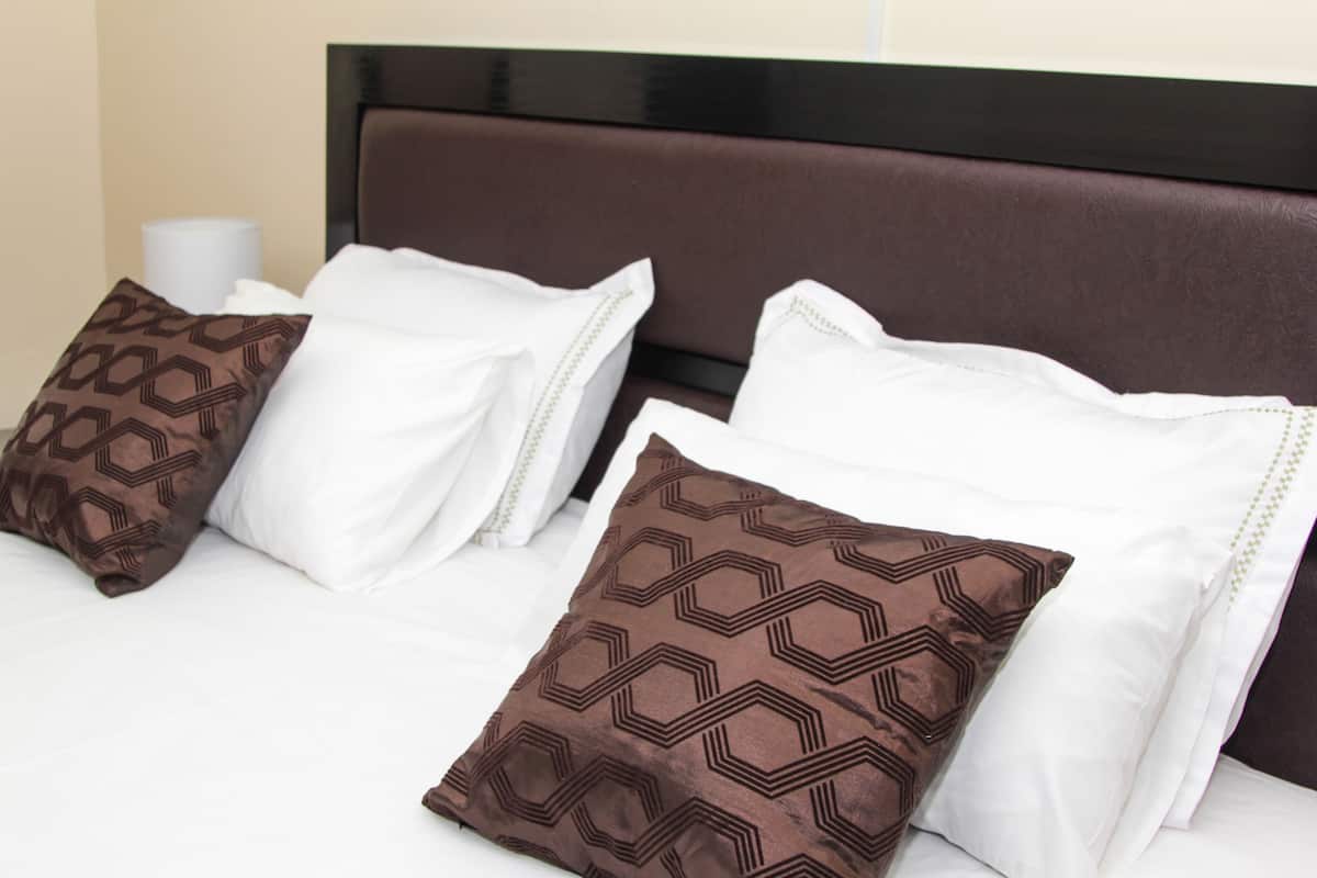 A neatly made bed with patterned pillows and a headboard.