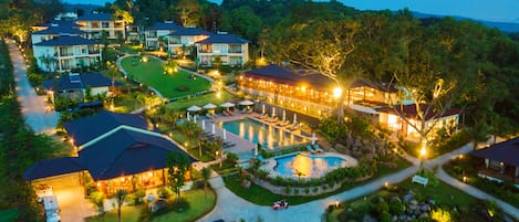 A resort with multiple buildings, a swimming pool, and well-maintained gardens.