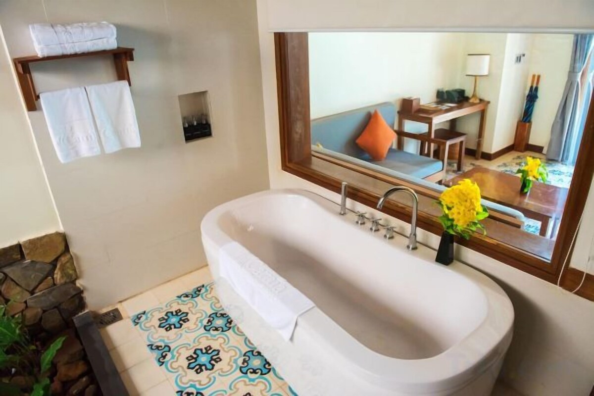 A bathroom with a bathtub, a mirror, and a tiled floor.