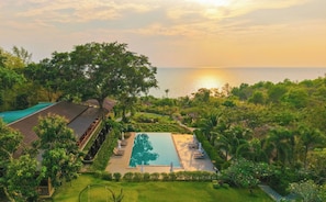A resort with a swimming pool, a covered walkway, and lush greenery. - Camia Resort & Spa (Phu Quoc)