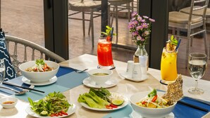 A dining table set with various dishes, drinks, and a vase of flowers. - TUI BLUE Nha Trang (Nha Trang)