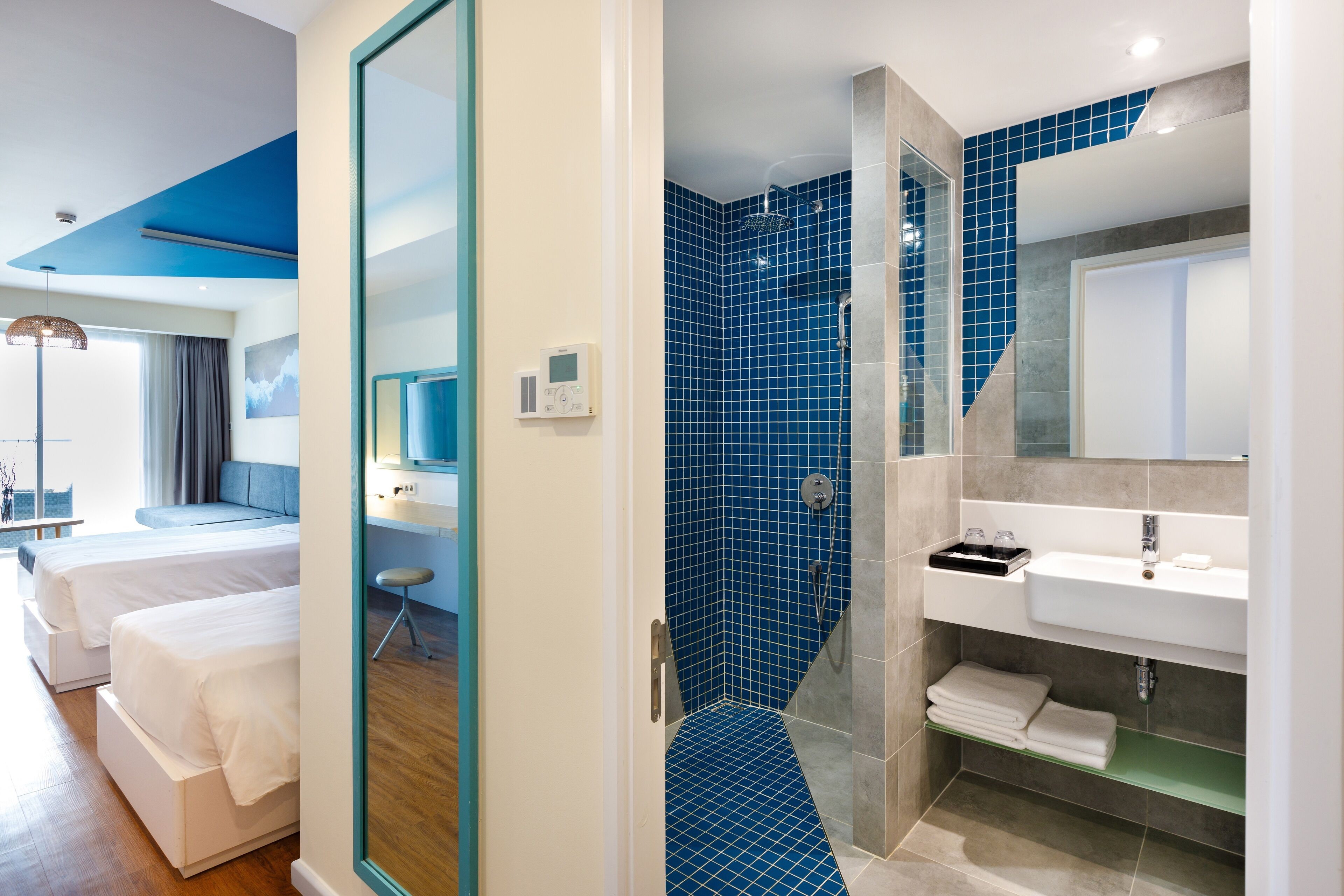 Habitació d'hotel moderna amb un llit gran, una dutxa, un lavabo i un mirall.
