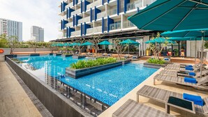 A rooftop swimming pool with lounge chairs and umbrellas, surrounded by a modern building with balconies. - TUI BLUE Nha Trang (Nha Trang)