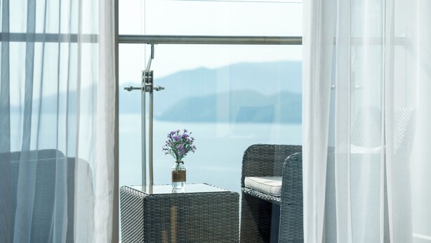 A balcony with wicker furniture, a glass table, and a vase with flowers. - TUI BLUE Nha Trang (Nha Trang)