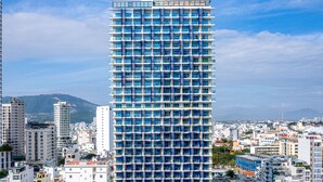A high-rise hotel with a blue and white facade, multiple balconies, and a rooftop pool area. - TUI BLUE Nha Trang (Nha Trang)