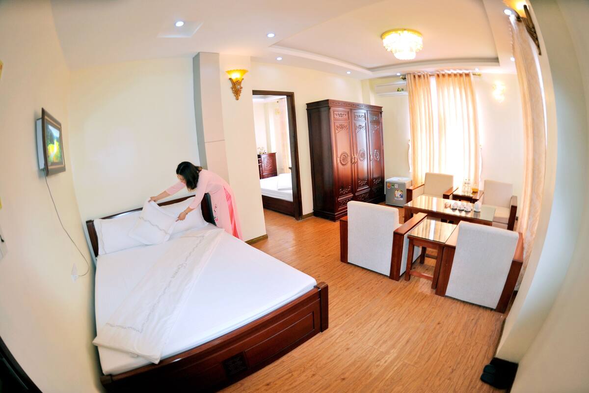 A hotel room with a bed, a desk, a chair, and a wardrobe.