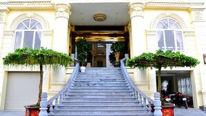 Una entrada imponente con una escalera que lleva a la entrada del edificio, flanqueada por dos grandes macetas.