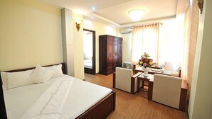 Una habitación de hotel con una cama grande, un escritorio con silla, un armario y una ventana con cortinas.