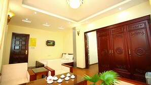 Habitación de hotel con armario de madera, sofá, mesa con teteras, cama y una planta pequeña.
