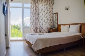 A bedroom with a large bed, a nightstand, a mirror, and a window with floral curtains. - Hotel Seril 1 (Fethiye)
