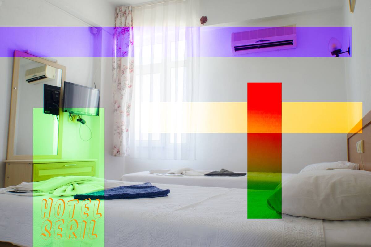 Quarto de hotel com cama, escrivaninha com computador, espelho e janela com cortinas.