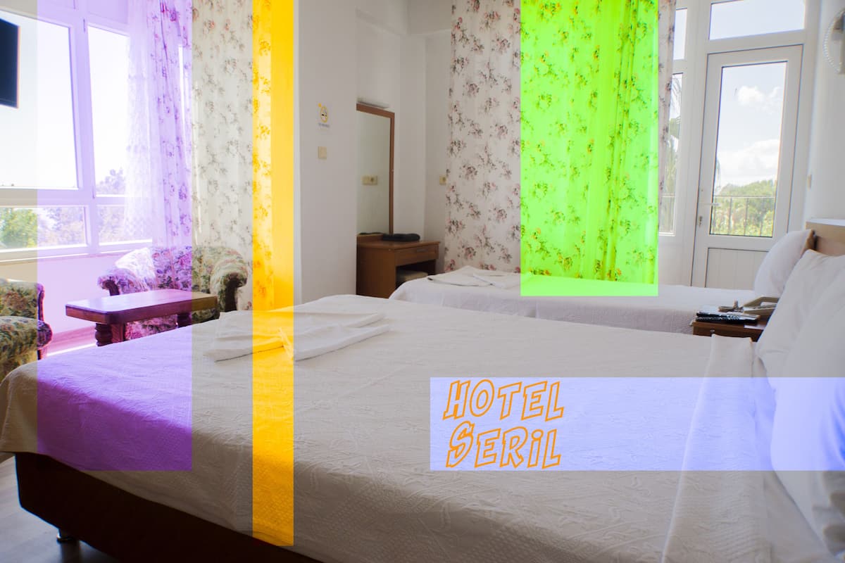 Quarto de hotel com duas camas, uma escrivaninha, uma cadeira e uma janela com cortinas.