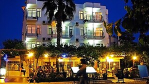 A multi-story hotel with balconies, a paved outdoor area, and palm trees. - Hotel Seril 1 (Fethiye)