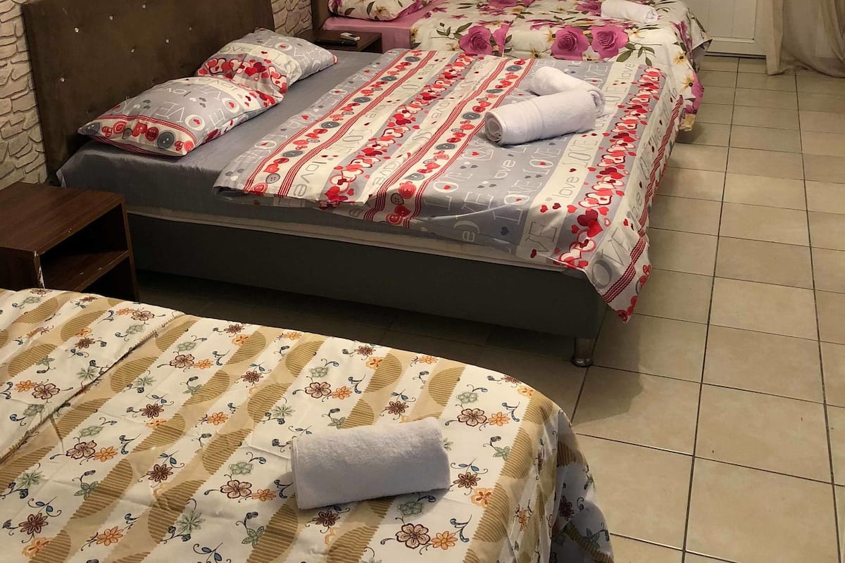 A hotel room with a stone-patterned wall, a chandelier, and two beds with floral bedding.