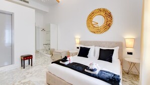 A modern hotel room with a large bed, a round mirror, a chandelier, and a marble floor. - Queen Palace Suites (Rome)