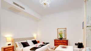 A hotel room with a bed, bedside tables, a dresser, a dining table with breakfast, and a mirror. - Queen Palace Suites (Rome)