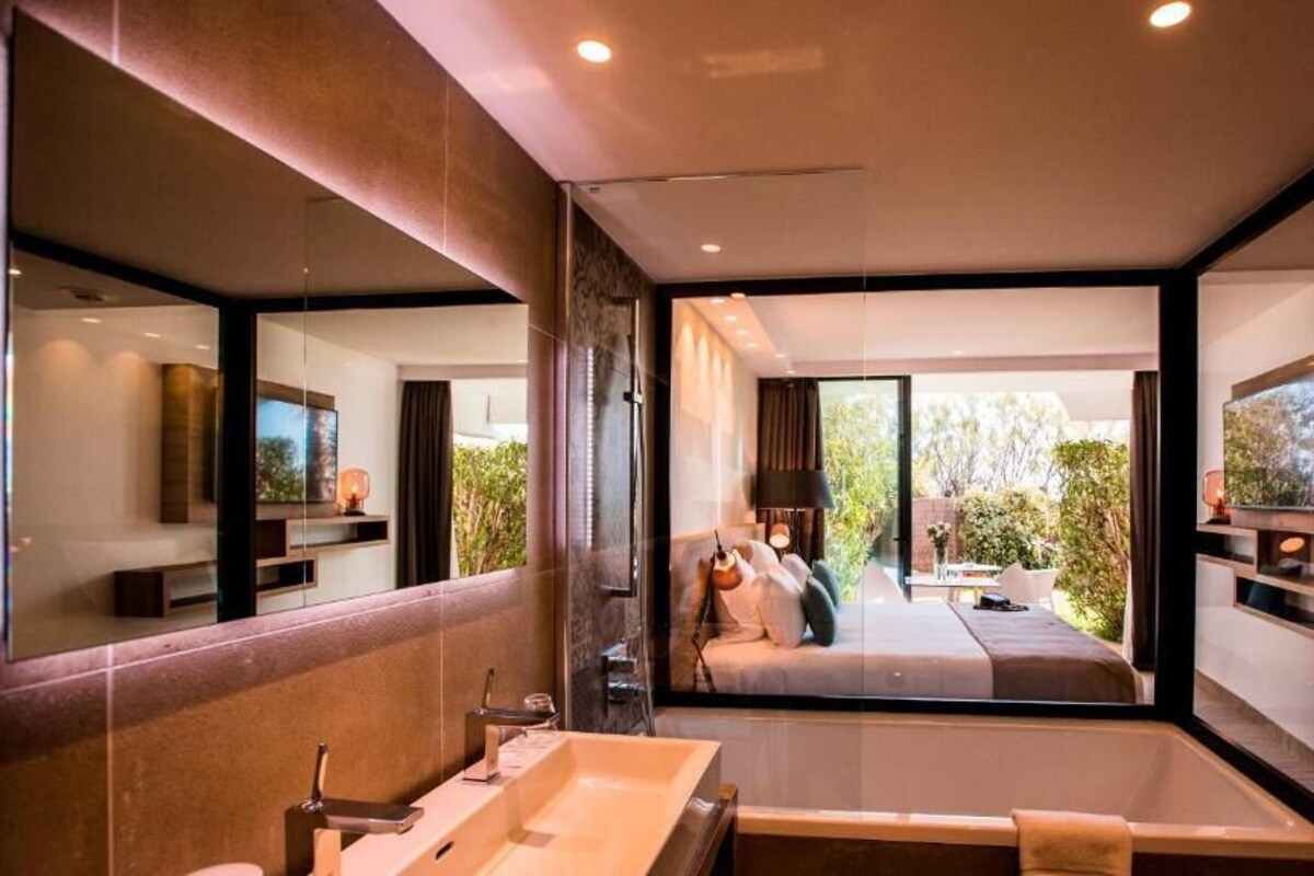 A modern bathroom with a large mirror, a bathtub, and a shower area.
