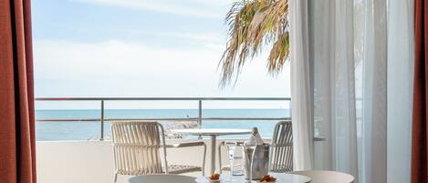 Un balcón con mesa y sillas, con vistas a una playa y el mar.