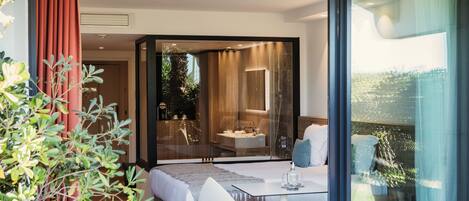 A modern bedroom with a bed, bedside tables, and a glass-enclosed bathroom.