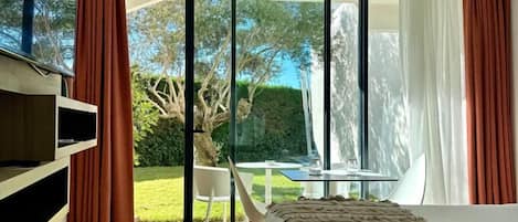 A modern bedroom with a large sliding glass door leading to a garden.