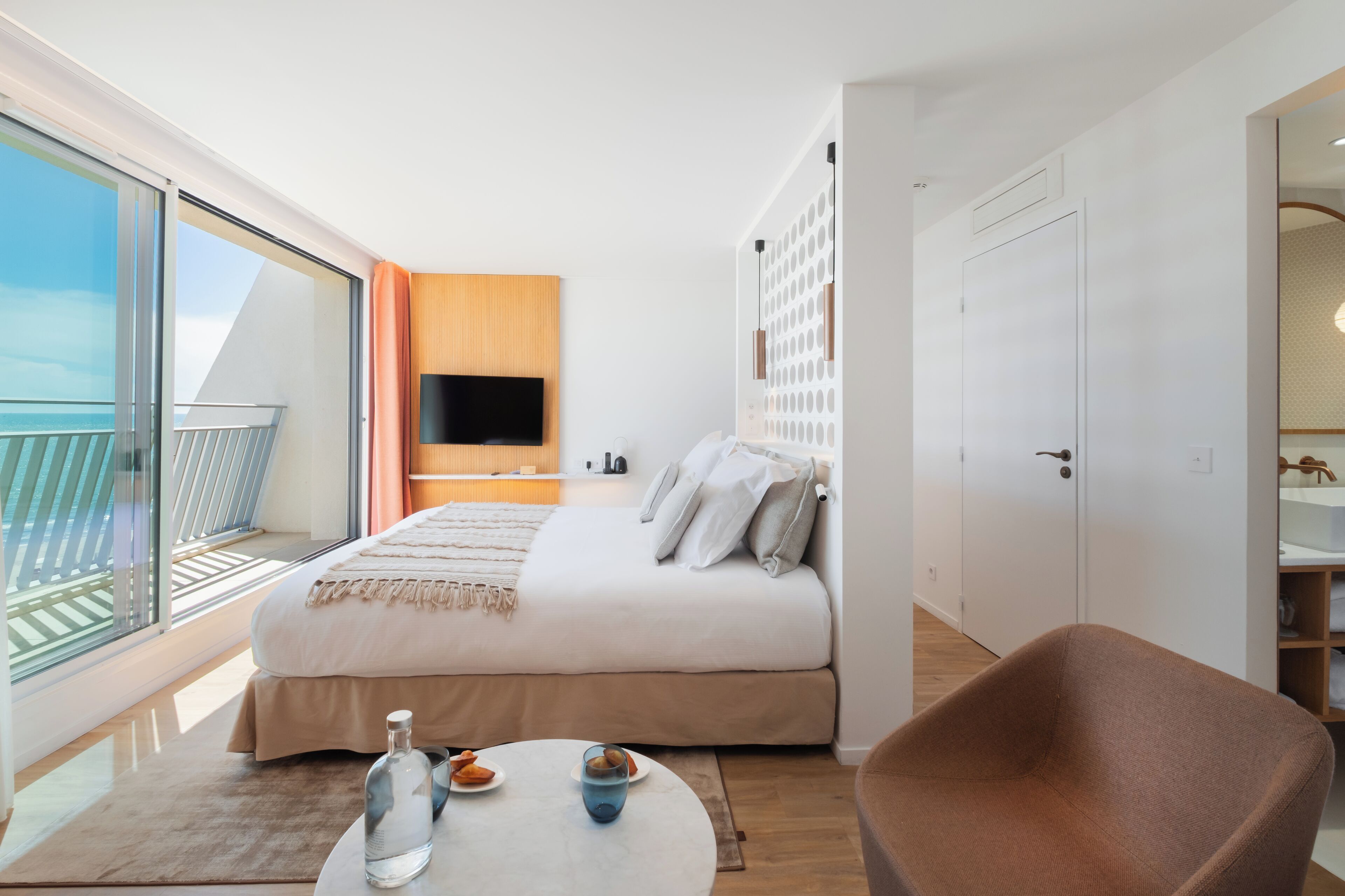 Une chambre d’hôtel moderne dotée d’un balcon, d’un lit, d’une télévision et d’un coin salon.
