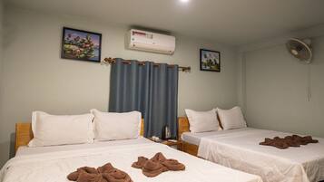A hotel room with two beds, a ceiling fan, an air conditioning unit, and two framed pictures on the wall.