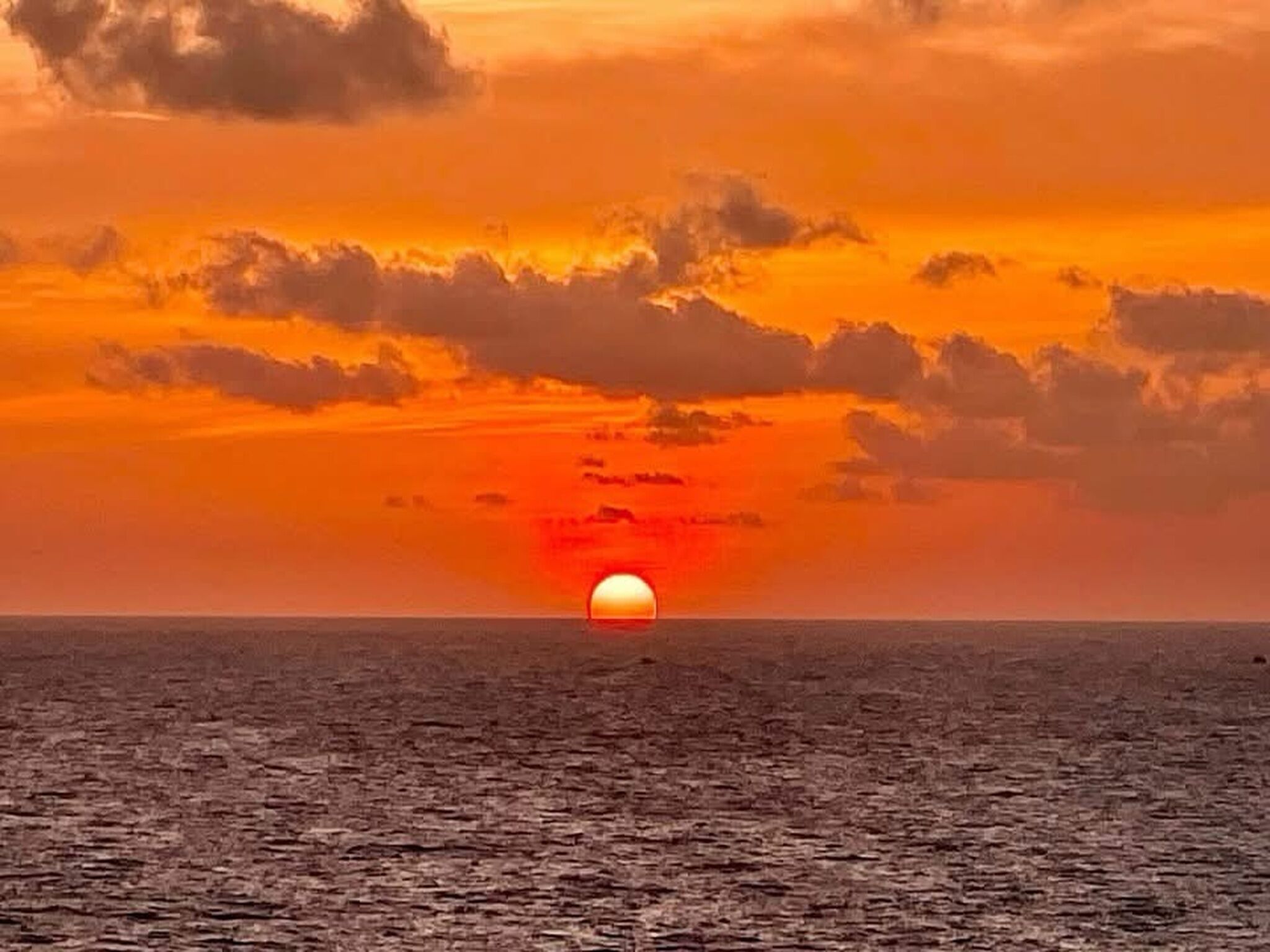 A sunset over a body of water with clouds in the sky.