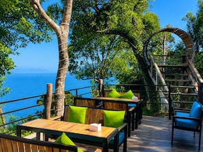 A wooden deck with outdoor seating, a staircase, and a view of the sea. - The Cliff Hostel (Koh Rong Sanloem)