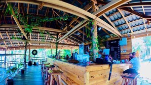 A wooden bar area with stools, a menu board, and a 'Tip Box' sign. - The Cliff Hostel (Koh Rong Sanloem)