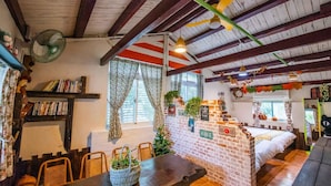 A cozy room with a brick partition, a bed, a dining table with chairs, and a bookshelf. - Cat Sky Country Homestay (Sanxing)