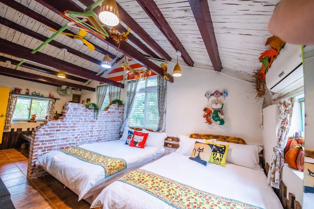 A cozy room with two beds, a brick wall, and a wooden ceiling.