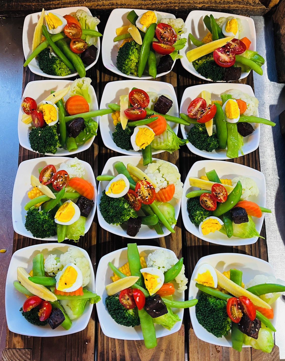A tray of neatly arranged food items including vegetables, rice, and eggs.