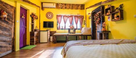 Um quarto aconchegante com uma cama, uma mesinha, uma TV e uma janela com cortinas.