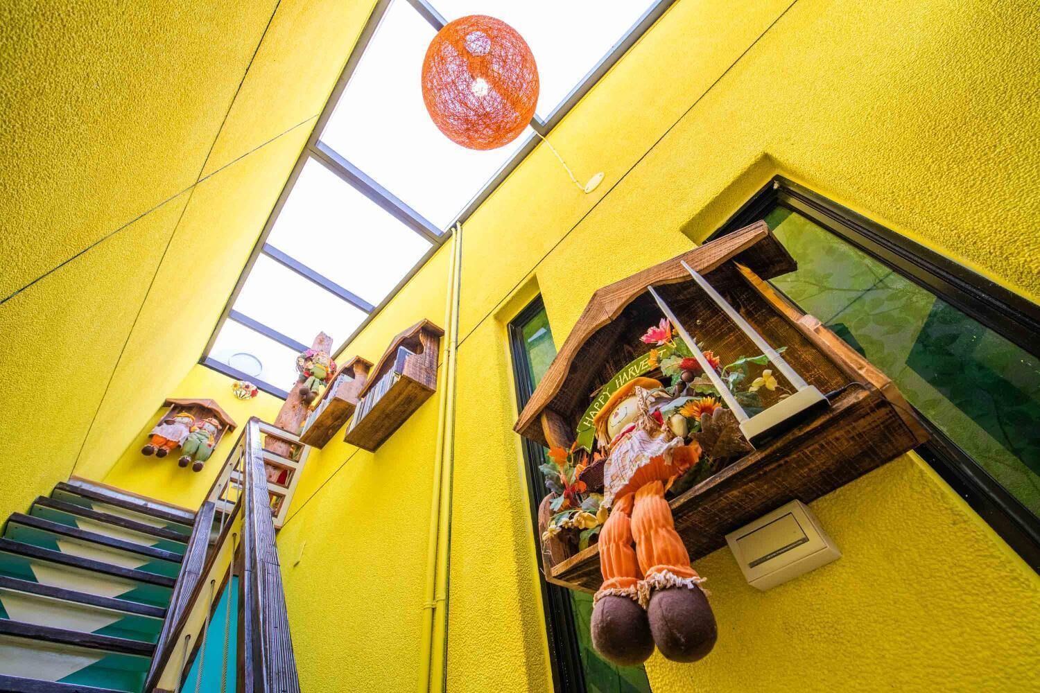 A bright yellow building with a skylight, wooden window boxes, and a staircase.