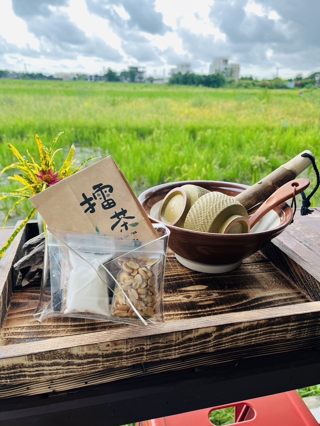A wooden tray with a bowl of rice, a wooden scoop, a plastic bag of rice, and a card with Chinese characters.