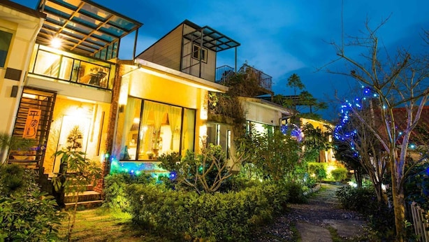 A modern house with a glass facade, a balcony, and a well-lit garden at night. - Cat Sky Country Homestay (Sanxing)