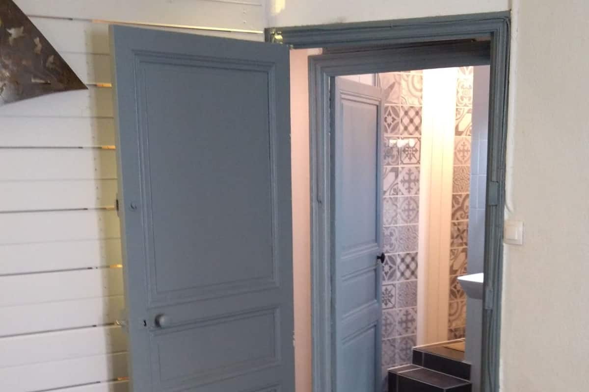 Una habitación con una puerta cerrada, un banco y un papel tapiz decorado al fondo.