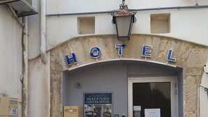 A hotel entrance with a sign reading "HOTEL" above the door. There is a sign for the "MAUGUIO CENTER HOTEL" with contact information and a photo of the interior. - Mauguio Center Hôtel (Mauguio)