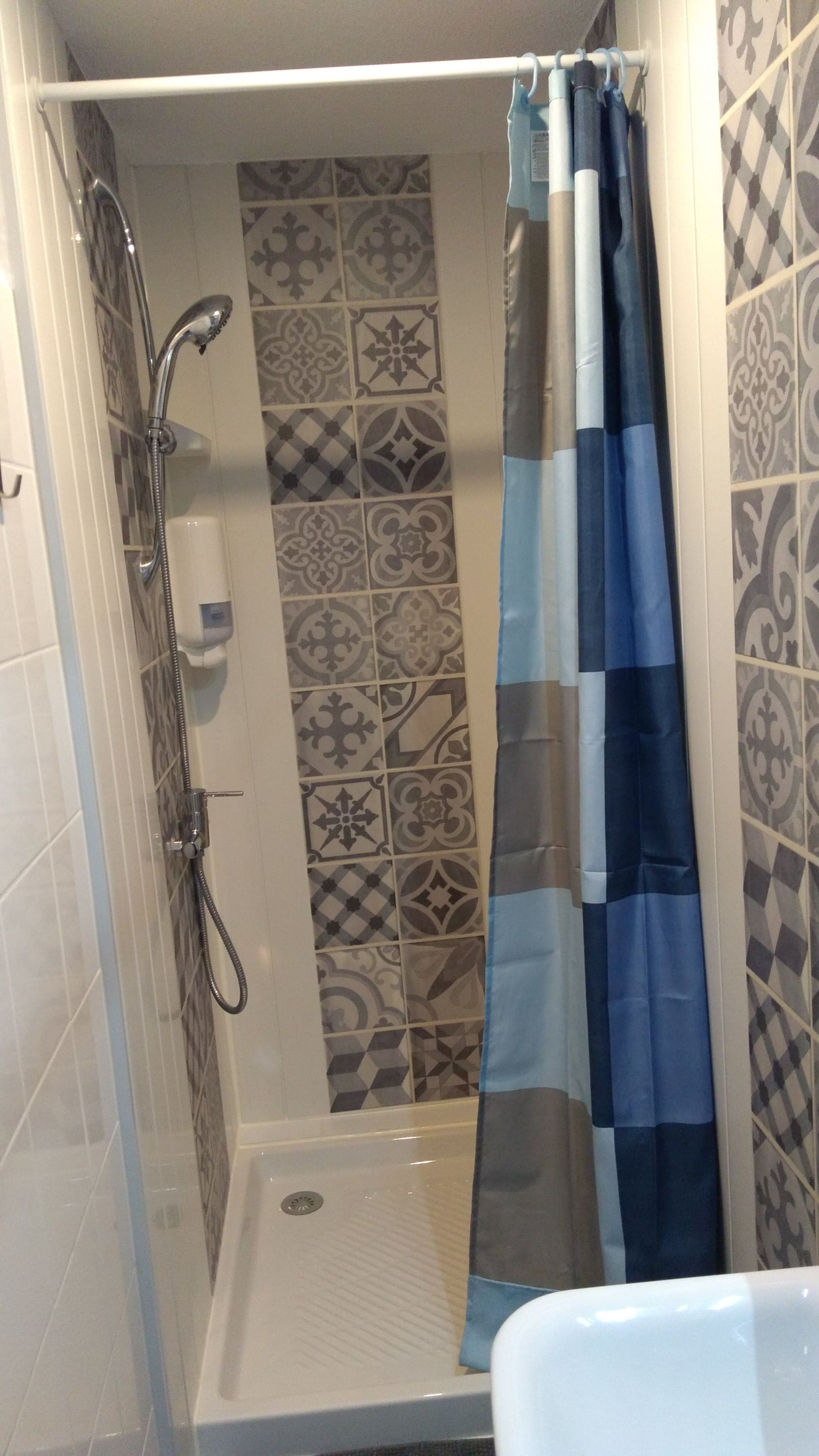 A shower with a glass door, a showerhead, and a curtain.