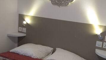 Een hotelkamer met een bed, een decoratief wandobject en bedlampjes.