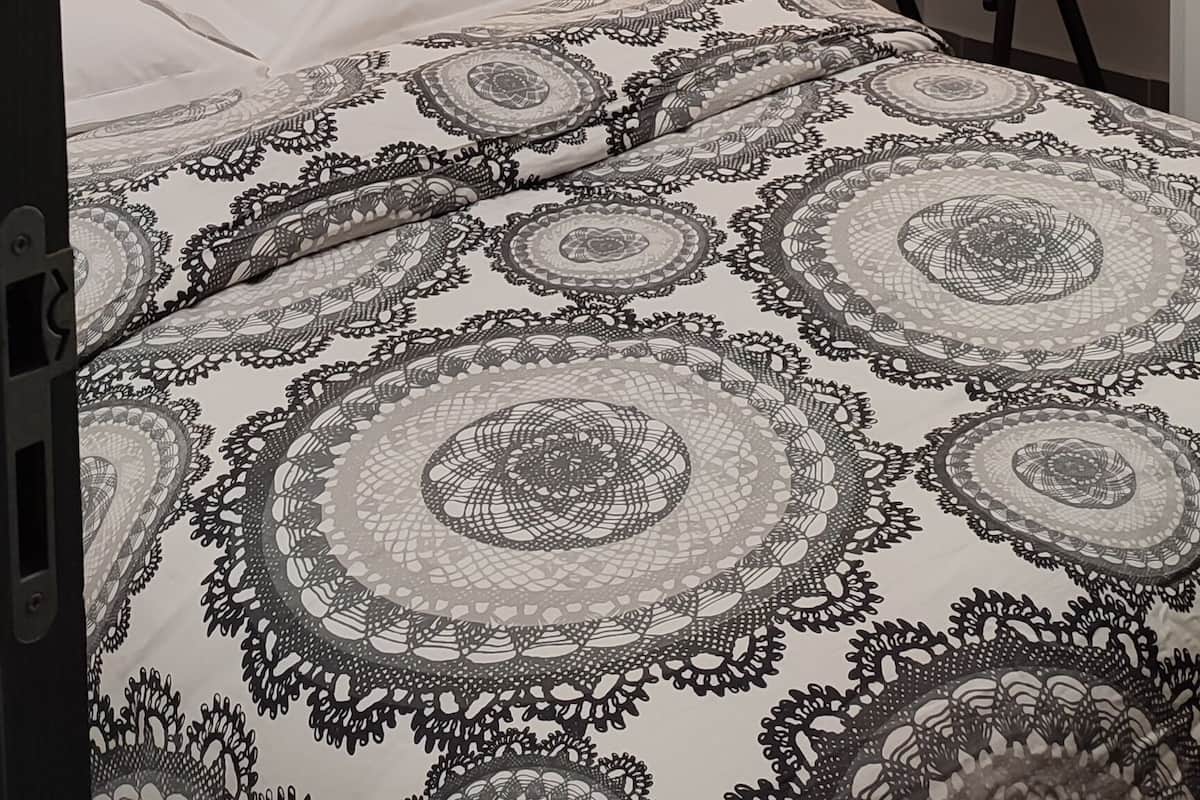 Un dormitorio con cama, escritorio, silla, lámpara de pared y un cuadro en la pared.